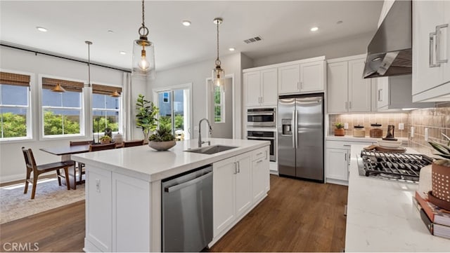 kitchen featuring dark wood-type flooring, wall chimney range hood, sink, white cabinetry, and stainless steel appliances