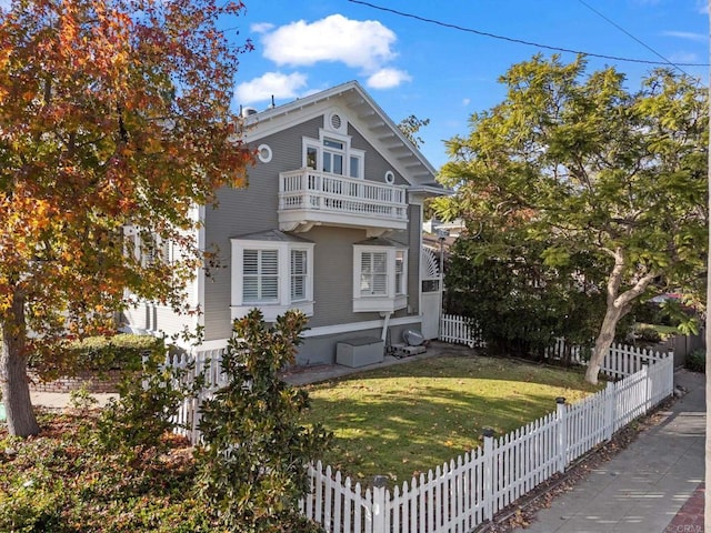 view of front of house featuring a balcony and a front lawn