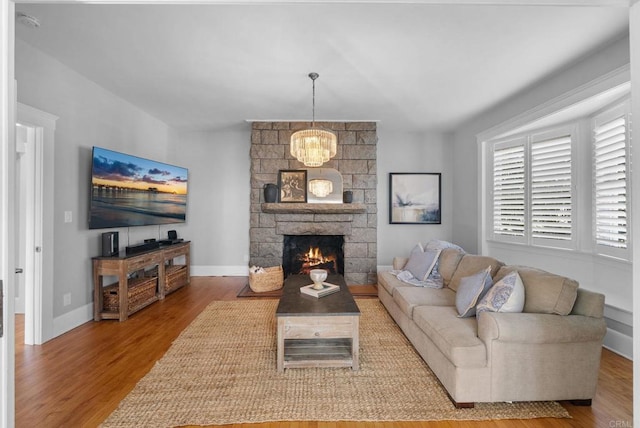 living room featuring a fireplace, wood-type flooring, and an inviting chandelier