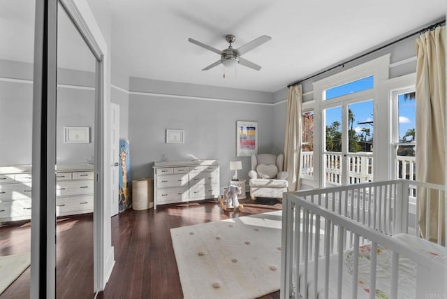 bedroom featuring a crib, ceiling fan, and dark hardwood / wood-style floors