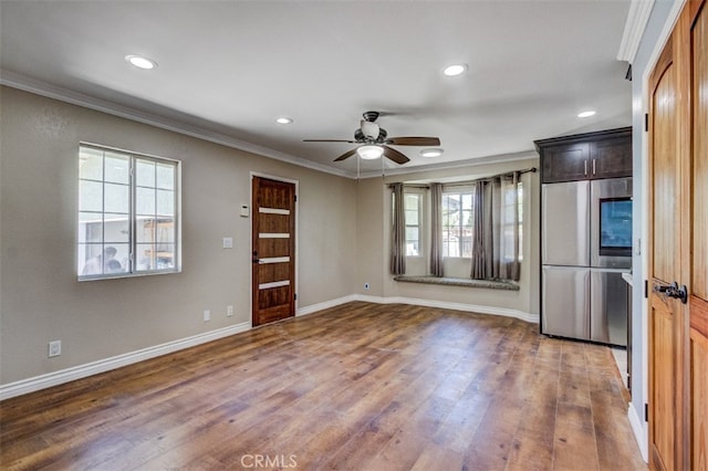 interior space with ornamental molding, stainless steel refrigerator, plenty of natural light, and dark wood-type flooring