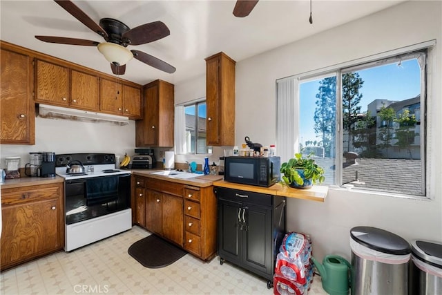 kitchen with under cabinet range hood, brown cabinetry, black microwave, and electric range oven