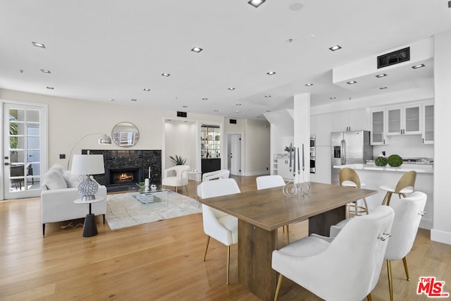 dining space featuring a healthy amount of sunlight, a high end fireplace, and light hardwood / wood-style floors