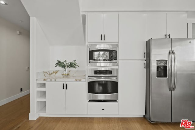 kitchen featuring white cabinetry, stainless steel appliances, light stone counters, and light hardwood / wood-style floors