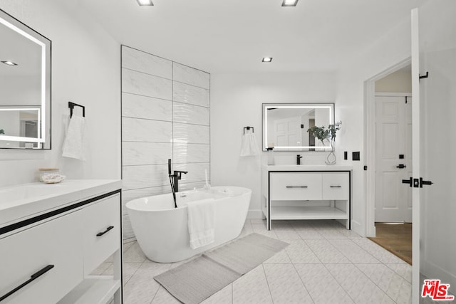 bathroom with a bathing tub, tile patterned flooring, and vanity