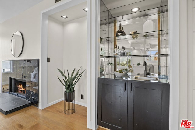 bar with a tiled fireplace, sink, and wood-type flooring