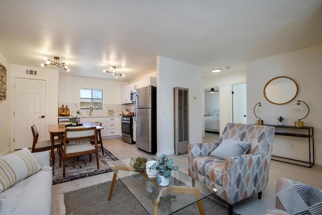 living room with ceiling fan with notable chandelier and sink