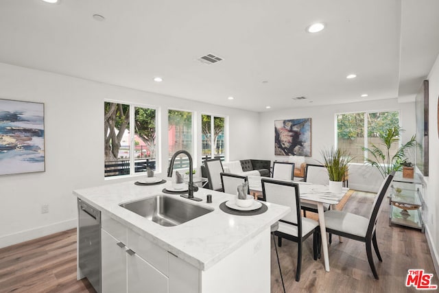 kitchen with a center island with sink, white cabinets, sink, stainless steel dishwasher, and a healthy amount of sunlight