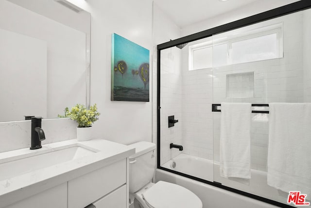 full bathroom featuring shower / bath combination with glass door, vanity, and toilet