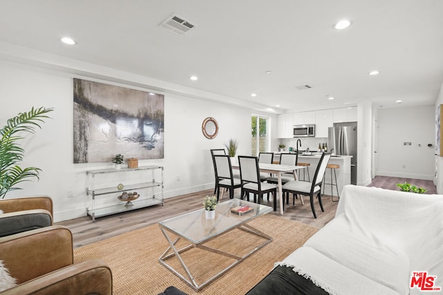 living room with light hardwood / wood-style flooring and sink