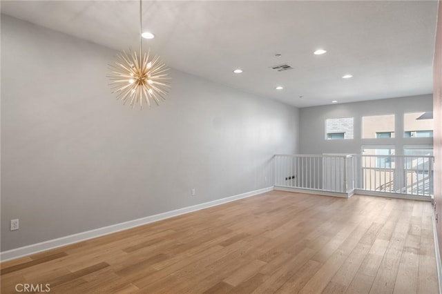 unfurnished room featuring a notable chandelier and hardwood / wood-style flooring