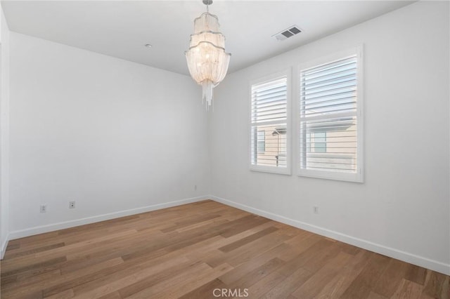 unfurnished room featuring hardwood / wood-style floors and an inviting chandelier