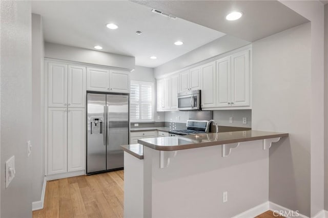 kitchen featuring kitchen peninsula, white cabinetry, and stainless steel appliances