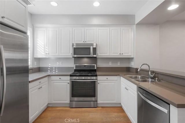 kitchen featuring stainless steel appliances, light hardwood / wood-style floors, white cabinetry, and sink