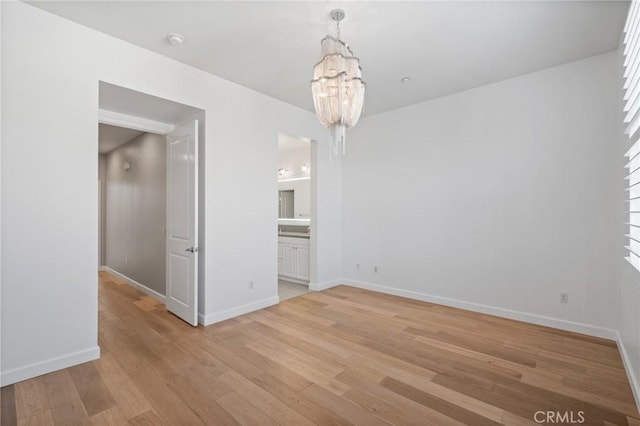 empty room featuring a notable chandelier and light hardwood / wood-style floors