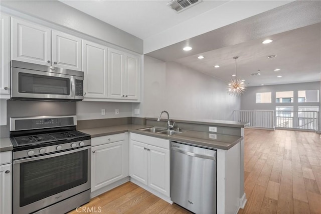 kitchen featuring light hardwood / wood-style floors, kitchen peninsula, sink, stainless steel appliances, and white cabinets