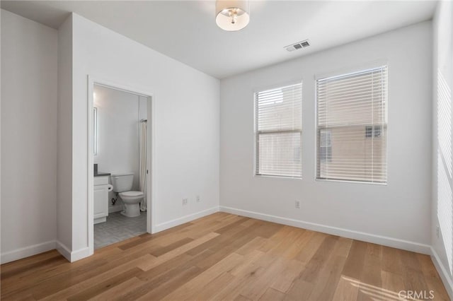 unfurnished bedroom featuring light hardwood / wood-style floors and connected bathroom