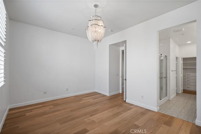 spare room featuring light hardwood / wood-style floors and an inviting chandelier