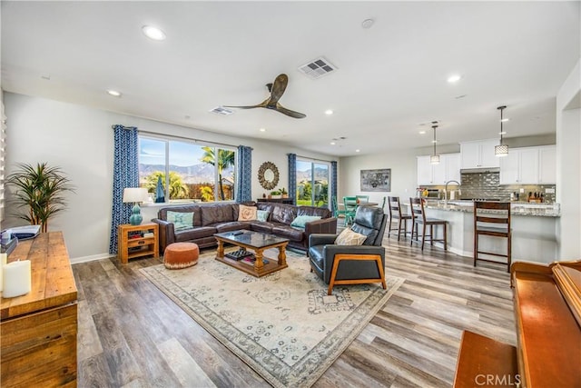 living room featuring ceiling fan, sink, and light hardwood / wood-style floors