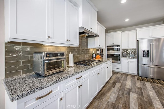 kitchen with dark wood-type flooring, white cabinets, tasteful backsplash, light stone counters, and stainless steel appliances