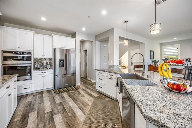 kitchen featuring white cabinetry, dark wood-type flooring, pendant lighting, and appliances with stainless steel finishes