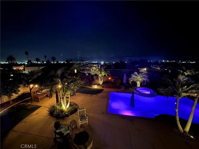 pool at twilight with an in ground hot tub and a patio