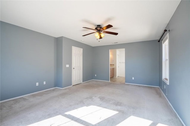 unfurnished bedroom featuring light carpet, connected bathroom, and ceiling fan