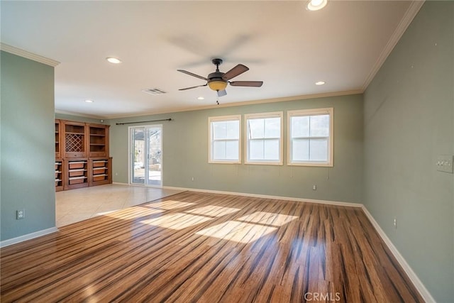 spare room featuring light wood-type flooring, ceiling fan, and crown molding