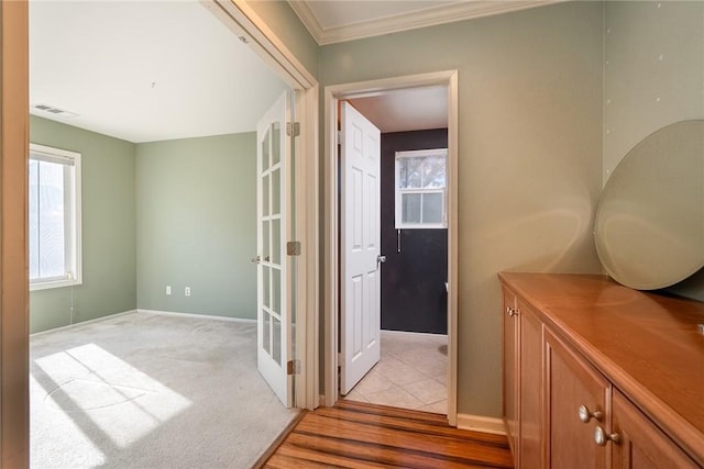 hall with ornamental molding and light carpet