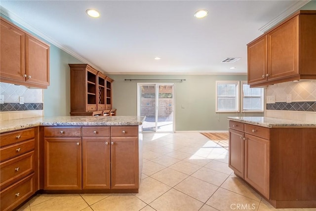 kitchen with backsplash, light stone countertops, light tile patterned floors, and ornamental molding