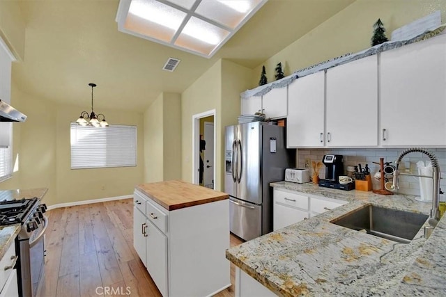 kitchen with sink, a kitchen island, light stone counters, white cabinetry, and stainless steel appliances