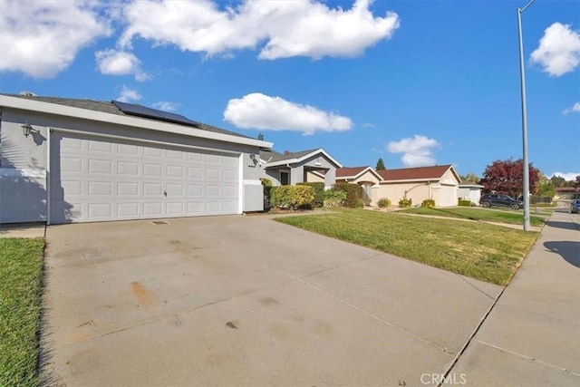 ranch-style home featuring a garage, a front yard, and solar panels