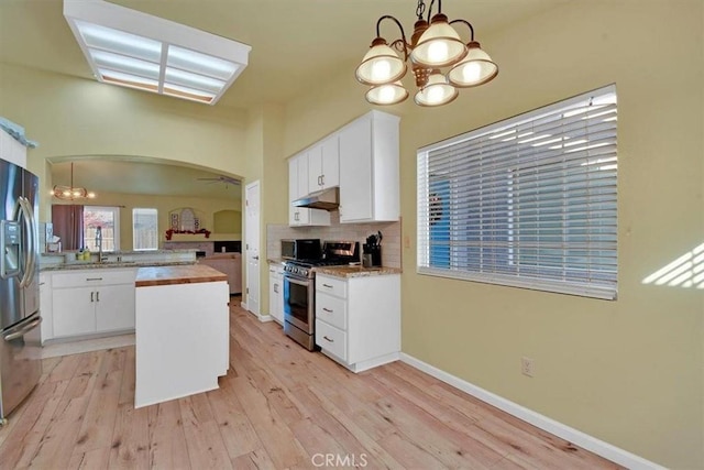 kitchen with wood counters, appliances with stainless steel finishes, light hardwood / wood-style flooring, white cabinets, and hanging light fixtures