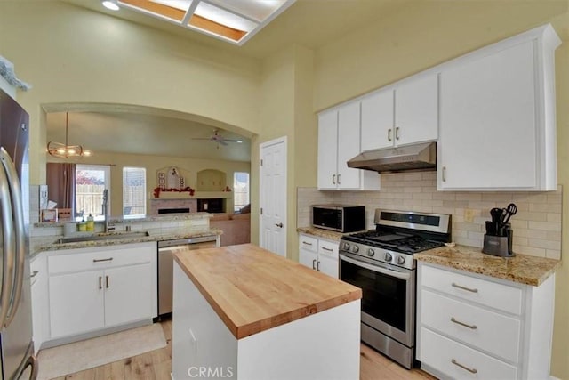 kitchen with appliances with stainless steel finishes, ceiling fan with notable chandelier, a kitchen island, sink, and white cabinetry