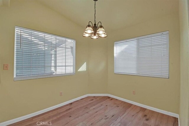 spare room with light wood-type flooring and a chandelier