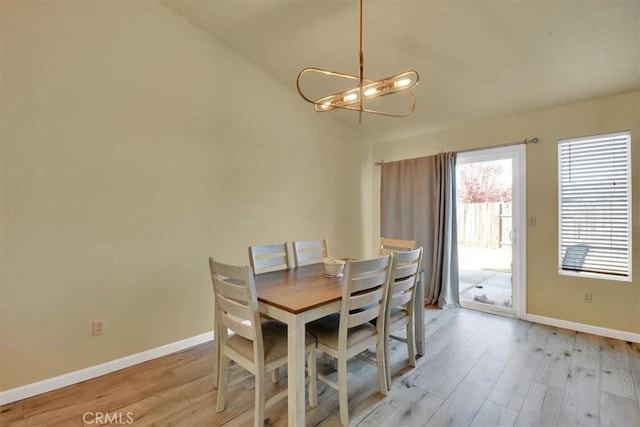 dining area with an inviting chandelier, lofted ceiling, and light wood-type flooring