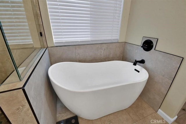 bathroom featuring tile patterned flooring, a bath, and tile walls