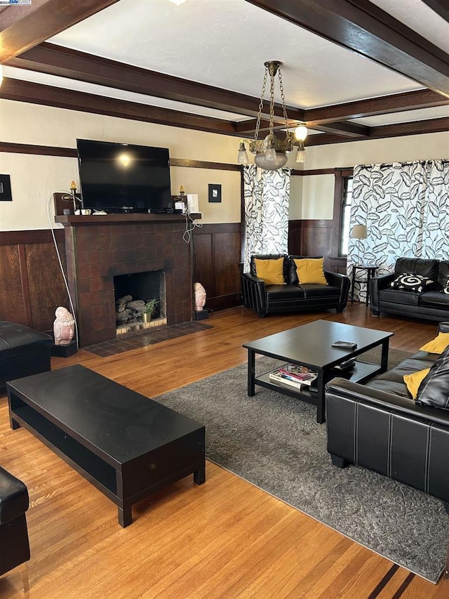 living room featuring beam ceiling, a chandelier, a fireplace, and light hardwood / wood-style floors