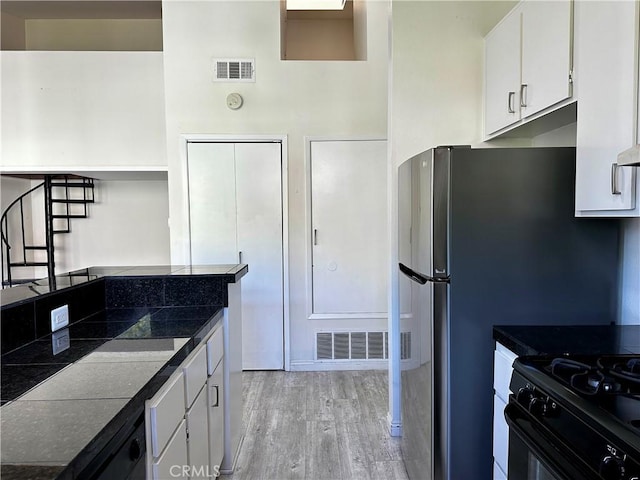 kitchen featuring light wood-type flooring, white cabinetry, and black range with gas stovetop