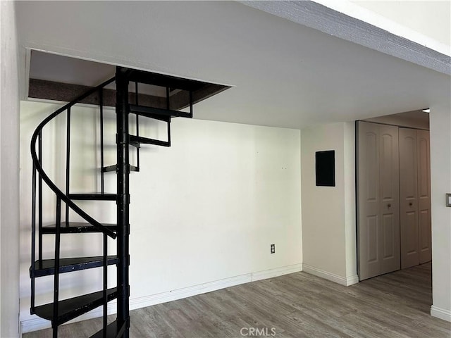 basement featuring electric panel and hardwood / wood-style flooring