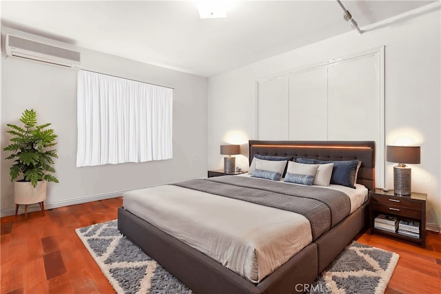 bedroom featuring wood-type flooring and a wall mounted AC