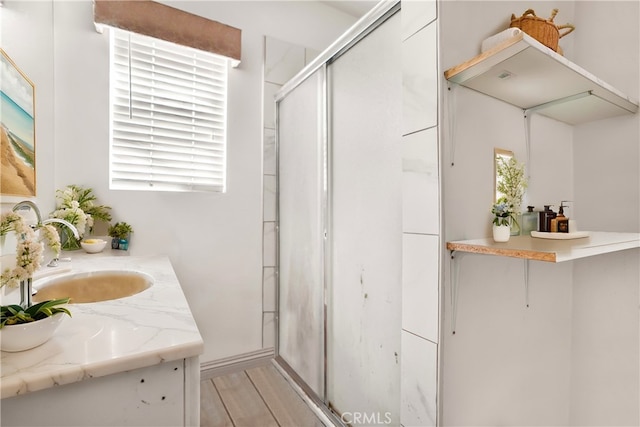 bathroom featuring a wealth of natural light, vanity, wood-type flooring, and walk in shower