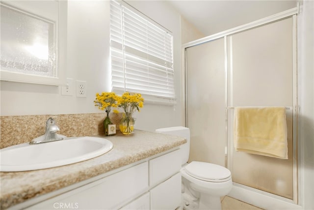 bathroom featuring vanity, a shower with shower door, and toilet