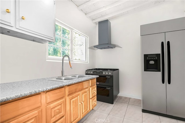 kitchen with light brown cabinetry, wall chimney exhaust hood, stainless steel built in refrigerator, black gas range oven, and sink