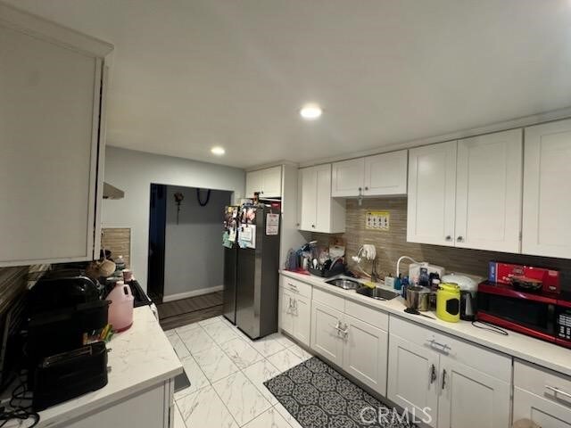 kitchen featuring sink, backsplash, white cabinetry, and black appliances