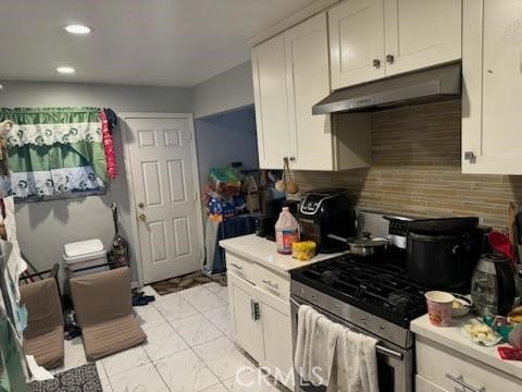 kitchen featuring white cabinets, backsplash, and stainless steel gas range oven