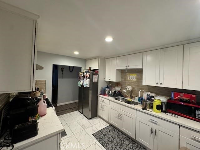 kitchen featuring decorative backsplash, sink, white cabinets, and black appliances