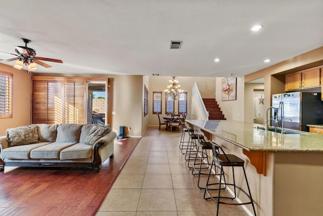 living room featuring light hardwood / wood-style flooring, ceiling fan with notable chandelier, and sink