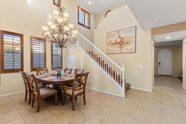 tiled dining space featuring a high ceiling and an inviting chandelier