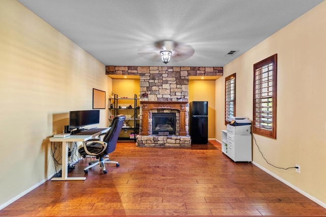 office featuring a fireplace, ceiling fan, and hardwood / wood-style floors